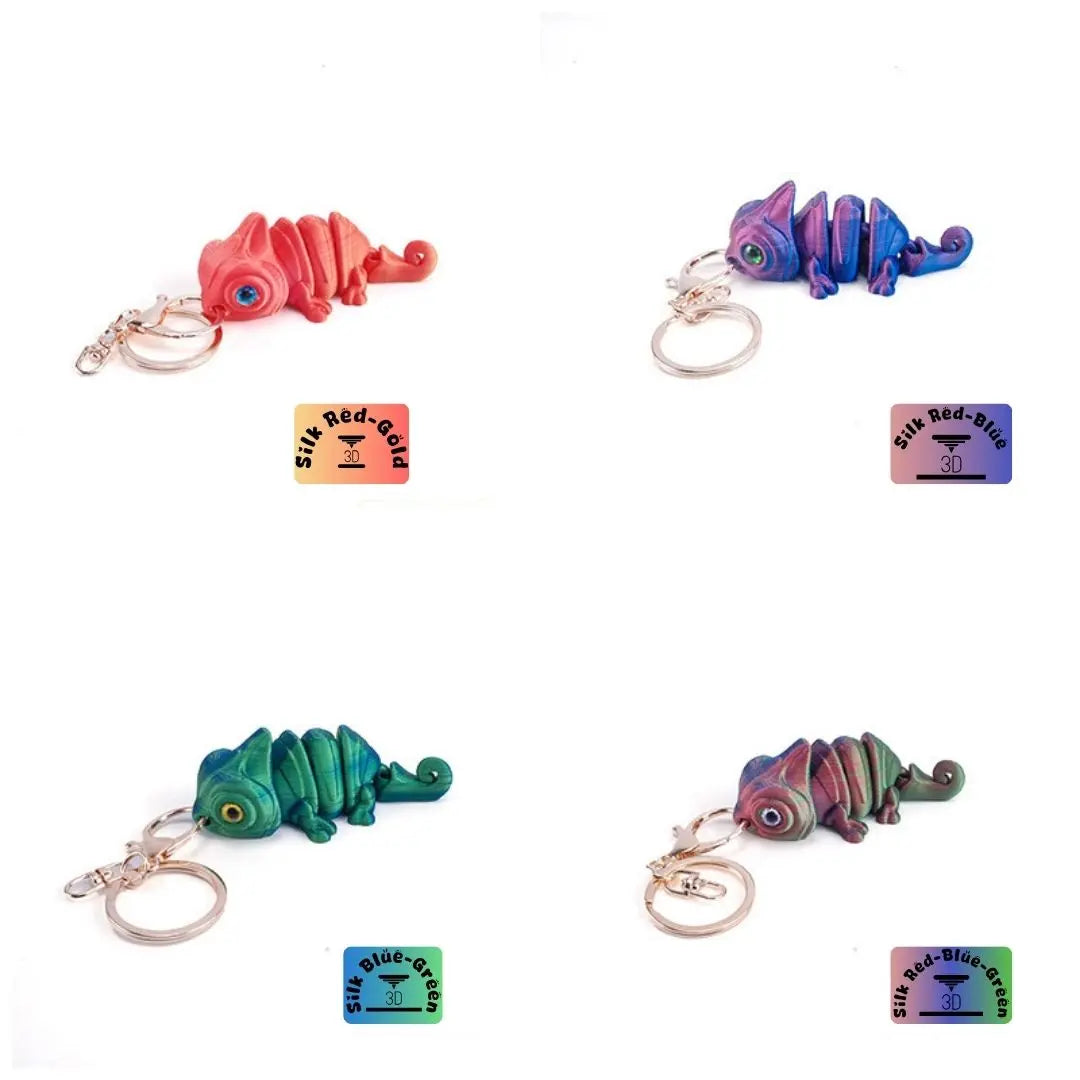 Collection of 3D printed chameleon keychains in vibrant colors including red-gold, blue-green, and red-blue-green. Each chameleon features distinct color patterns, gold eyes, and is attached to a gold-colored metal ring. The keychains are displayed against a white background, highlighting their unique designs and colors.